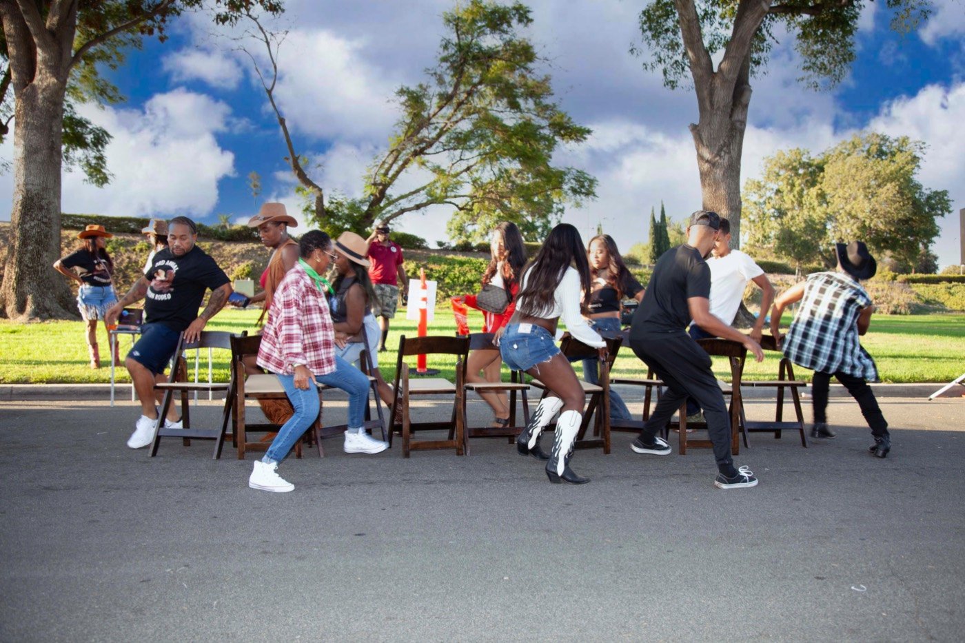 Neighbors playing musical chairs in cowboy hats and boots at the block party